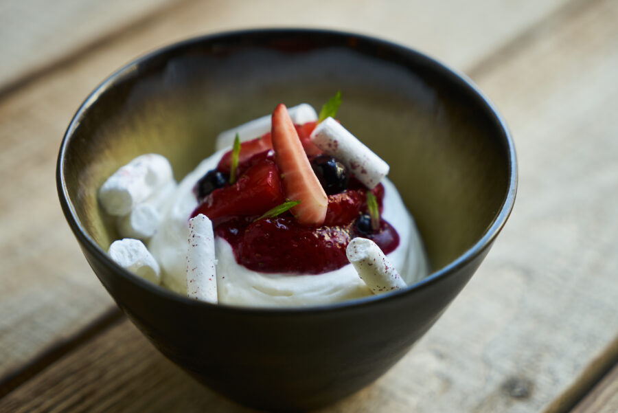 Estonian sweet dessert Kama with yoghurt mousse, wild berries and meringues, Ice cream with strawberries, currants and mint leaf