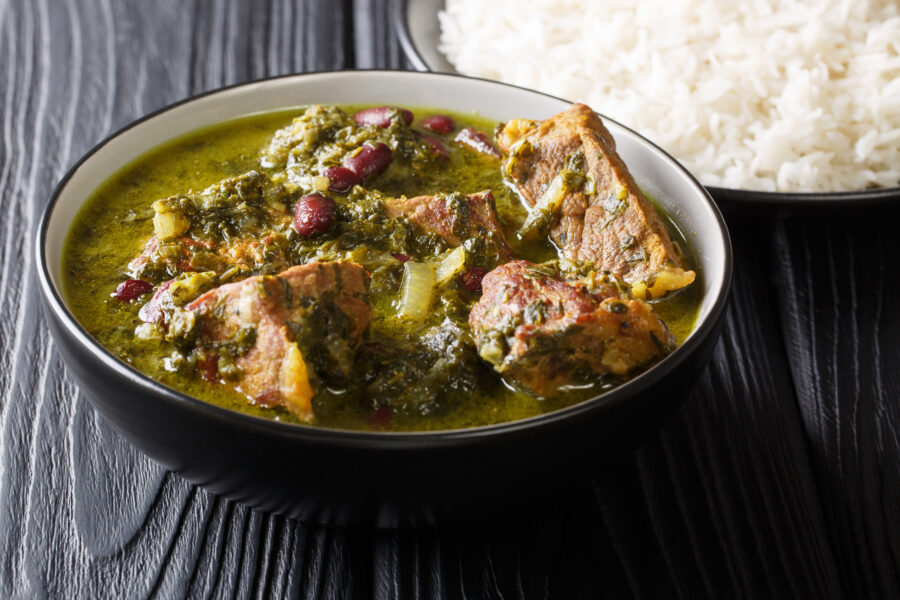 Freshly prepared Ghormeh Sabzi of lamb stew meat with herbs and beans close-up in a bowl and rice on the table. horizontal