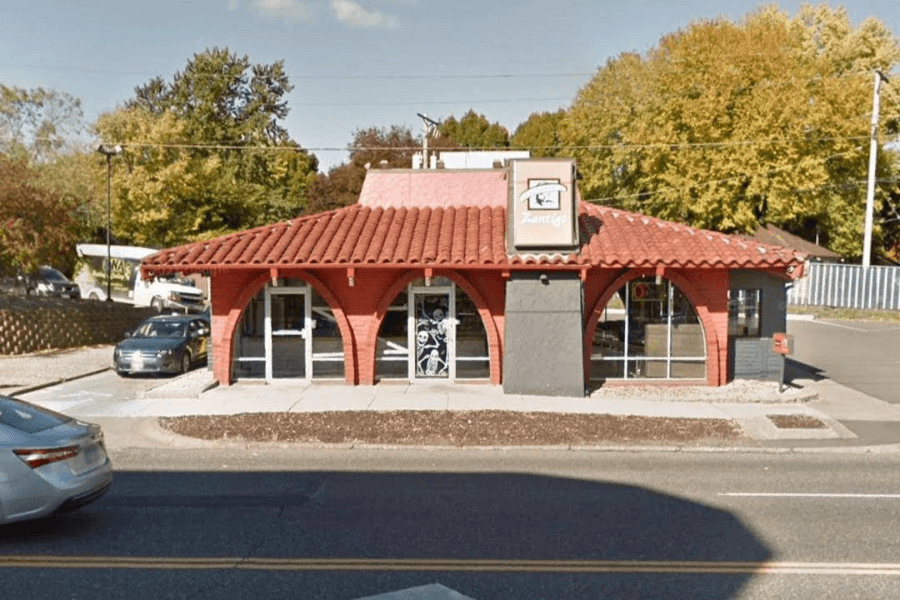 This image showcases the exterior of a classic fast-food restaurant building with distinctive Spanish-style architecture, featuring red roof tiles and arched windows, reminiscent of Taco Bell’s original design from decades past.
