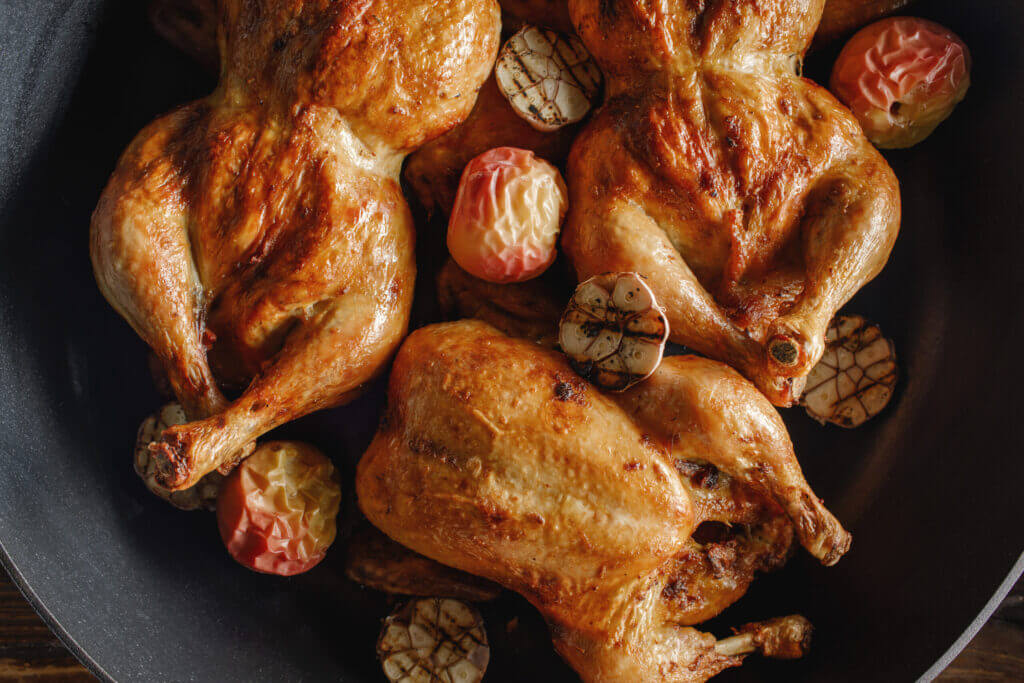 Roasted whole chicken with backed apples and garlic in iron cast pan